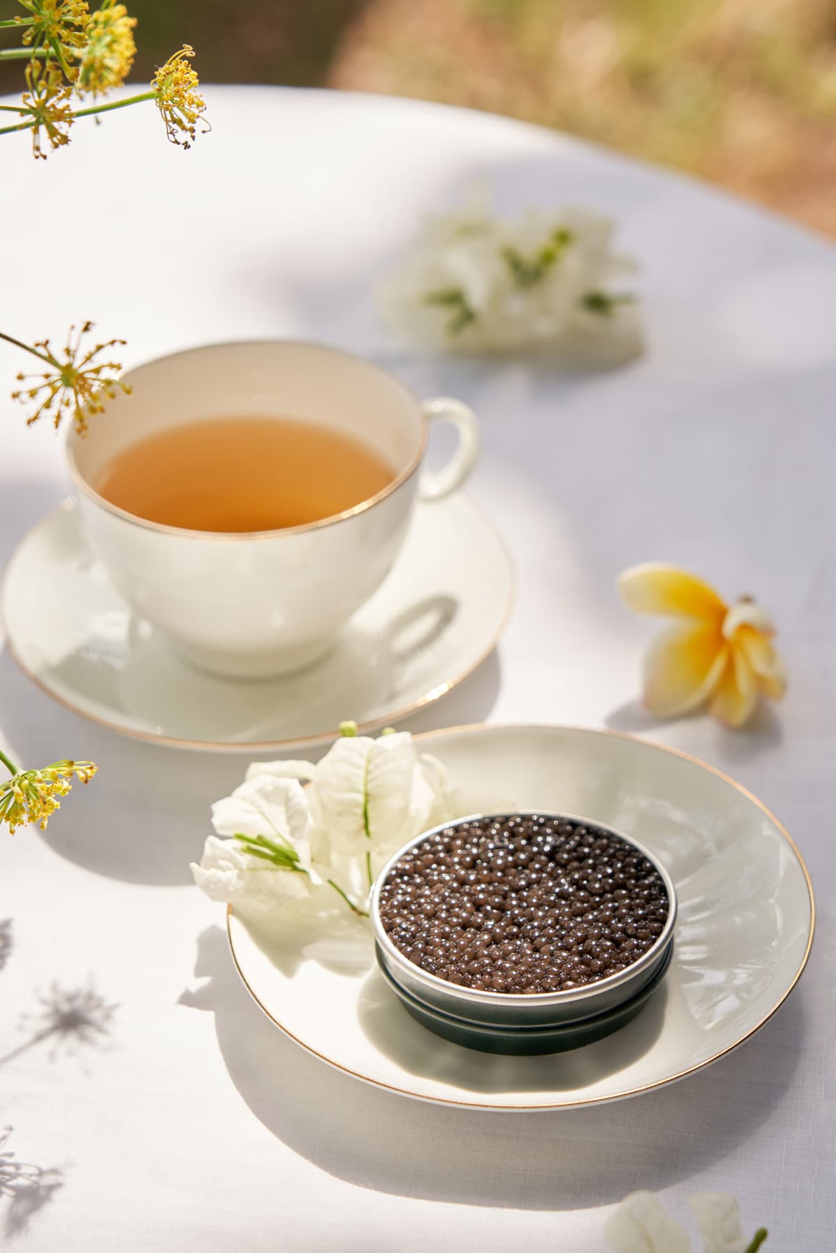 Caviar tin and cup of tea on a flowered table