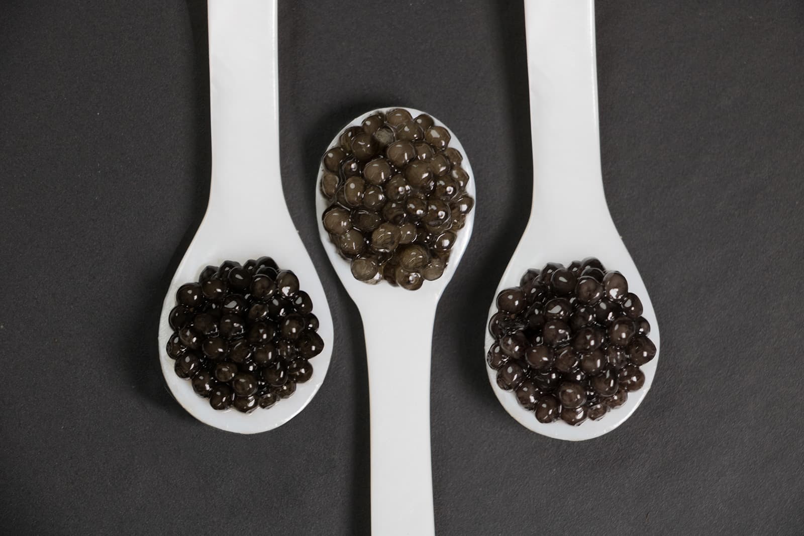 Three white spoons filled with different caviars