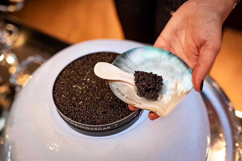 Caviar tasting on a mother-of-pearl dish with an ice dome in the background