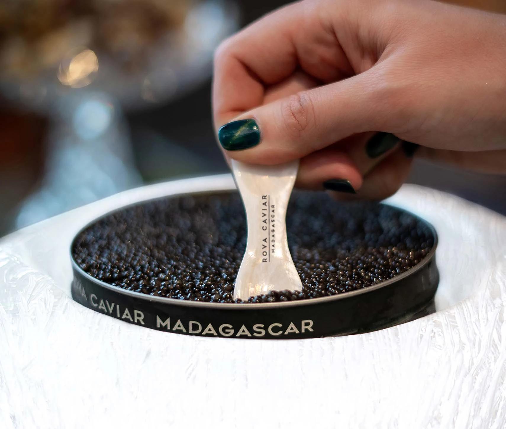 Hand using a mother-of-pearl spoon with caviar